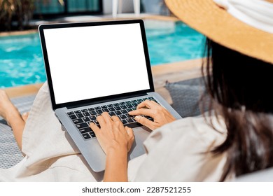 Freelancer using laptop working remotely near swimming pool. Young Asian traveler woman working on computer during her summer holiday. Work from anywhere, Technology and lifestyle concept, copy space - Powered by Shutterstock