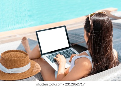 Freelancer using laptop working remotely near swimming pool. Young Asian traveler woman working on computer during her summer holiday. Work from anywhere, Technology and lifestyle concept, copy space - Powered by Shutterstock