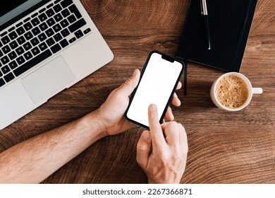 Freelancer using mobile phone with blank white mockup screen at office desk, top view - Powered by Shutterstock