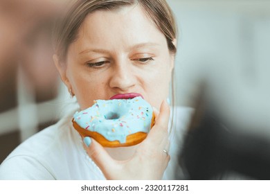 Freelancer woman eating unhealthy junk food while working from home. Attractive handsome young female feeling happy and enjoy, use laptop computer study learn online and eat donut in the kitchen