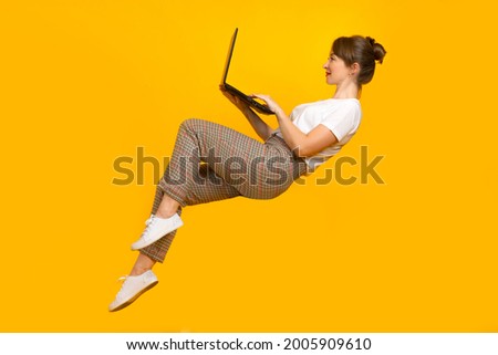 Freelancer woman with laptop. Freelance girl lies in zero gravity. Freelancer with a computer in an unusual pose. Freelancer works with a laptop. Creative portrait of a girl with a computer.