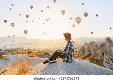 Freelancer working online at beautiful destination in Nevsehir, Goreme. Free inspired traveling blogger sitting alone on hill in scenic valley in Anatolia, Kapadokya