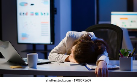 Freelancer working overtime on project falling asleep on desk with hand on financial documents trying to respect the deadline. Employee using modern technology network wireless, sleeping on table. - Shutterstock ID 1908571639