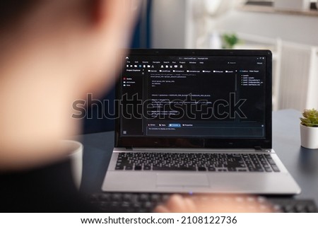 Freelancer writing code on laptop using keyboard. Freelance student programmer working remote developing software. Software coder looking for errors in home office. Code tester debugging.