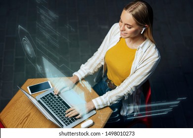 Freelancers of the future could be working with a digital HUD around them. A millennial young woman is working with her laptop and phone in a cafe, while a holographic projection encircles her.