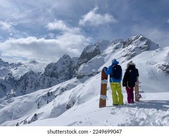 Freeride couple admiring endless possibilities for snowboarding fresh powder snow. Young woman and man holding snowboards on top of snowy mountain ridge. Amazing views in pristine Albanian mountains. - Powered by Shutterstock