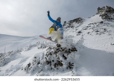 Freeride downhill snowboarding in the snowy mountains among rocks, winter freeride extreme sport.