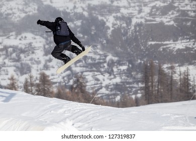 A free-ride ski jumper, with skis crossed against a mountains