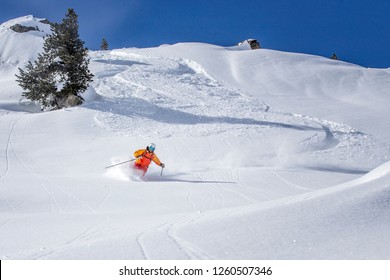 freeride skier skiing downhill through fresh powder snow