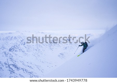 Freerider skiing in arctic far north from polar circle in cold conditions and freezing temperatures with a view on abandoned mountains of west coast in Greenland