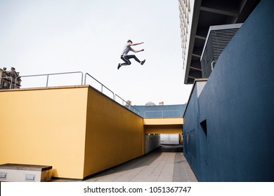 Freerunner is jumping beween colourful buildings in the city. 