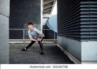 Freerunner is stretching his leg muscles on a rooftop.  - Powered by Shutterstock