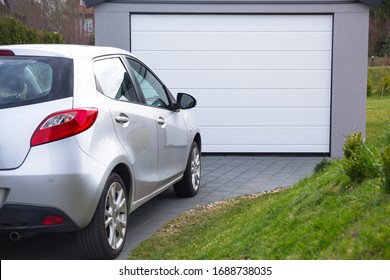 Free-standing garage in the garden with a car parked in front of the gate - Shutterstock ID 1688738035