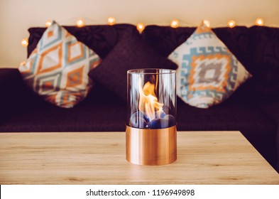 Freestanding Portable Glass And Copper Metal Fireplace Burning Bio Ethanol Gas On Living Room Wooden Table. Autumn Comfortable Colorful Cozy Home Set.
