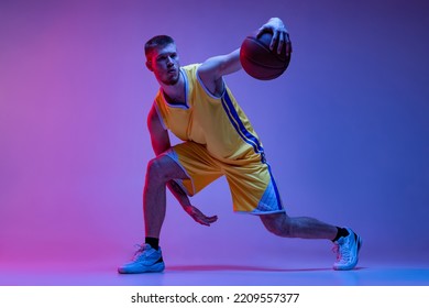 Freestyle basketball. Studio shot of muscled man, basketball player training with ball isolated on purple background in neon light. Concept of sport, achievements, competition, hobby, active lifestyle - Powered by Shutterstock