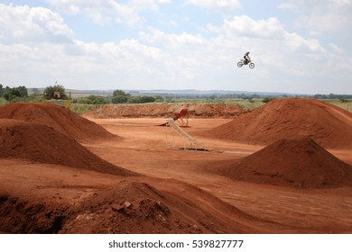 A Freestyle Motocross Or FMX Rider Clears A Jump In A Park.