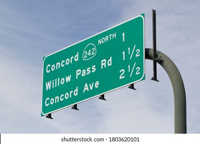 Freeway Exit Guide Sign Against Blue Sky And Clouds.