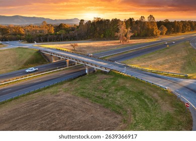 Freeway overpass junction with fast moving traffic cars and trucks in American rural area at sunset. Interstate transportation infrastructure in USA