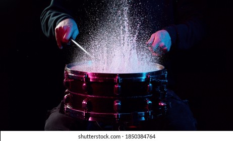 Freeze motion of drummer hitting drum with water splashes, isolated on black background