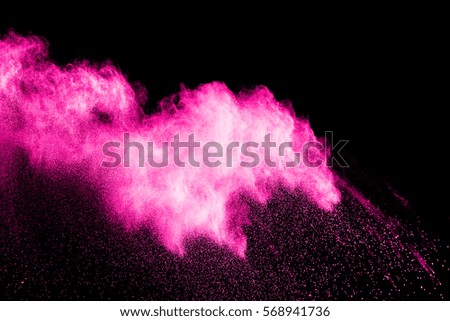Freeze motion explosion of pink dust on a black background. By throwing talcum powder out of hand. Stopping the movement of pink holi  powder on dark background.