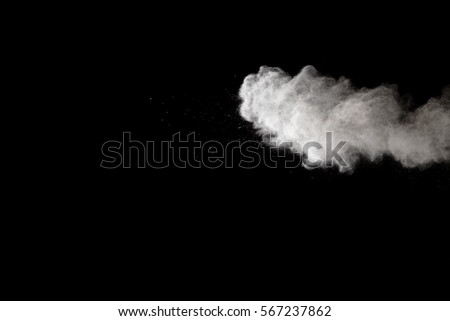 Freeze motion explosion of white dust on a black background. By throwing talcum powder out of hand. Stopping the movement of white powder on dark background.