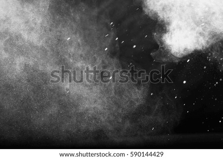 Freeze motion explosion of white dust on a black background. By throwing talcum powder out of hand.