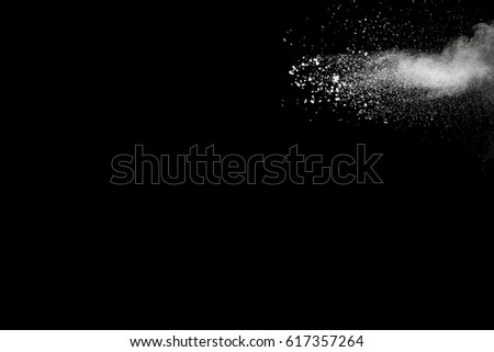Freeze motion explosion of white dust on  black background. By throwing talcum powder out of hand. Stopping the movement of white powder on dark background.