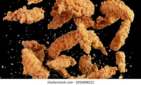 Freeze motion of flying pieces of fried chicken pieces on black background. Concept of levitating food. - Shutterstock ID 2056008221