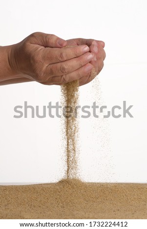 Freeze motion. Men's hands held in a handful of yellow sand which from below falls on a pile.