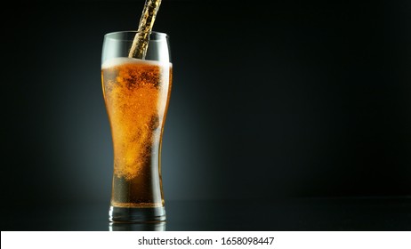 Freeze motion of pouring beer into glass pint, isolated on black background
