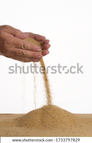 Freeze motion. Sand pours out of a handful. Close-up. White background. Side view.