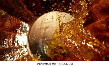 Freeze motion of splashing whisky in wooden barrel. Concept of pouring whisky, rum or cognac inside a keg. Alcoholic beverage background.