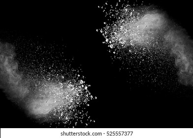 Freeze motion of white dust explosion on black background. Stopping the movement of white powder on dark background. Explosive powder white on black background.