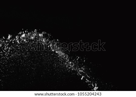 Freeze motion of white dust explosion on black background. Stopping the movement of white powder on dark background.