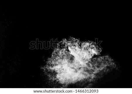 Freeze motion of white dust explosion on black background. Stopping the movement of white powder on dark background.
 Explosive powder white on black background.
