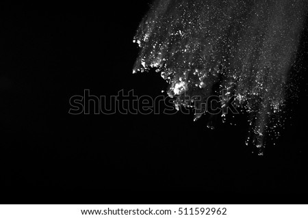 Freeze motion of white dust explosion on black background. Stopping the movement of white powder on dark background.