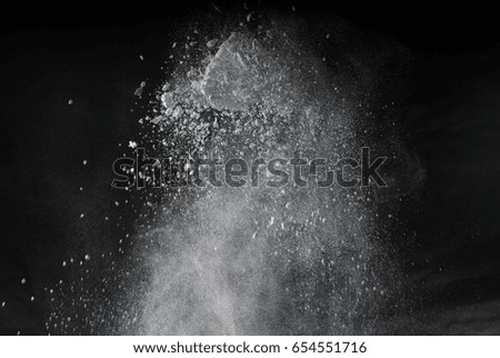 Freeze motion of white dust explosion on black background.. Stopping the movement of white powder on dark background. Explosive powder white on black background.