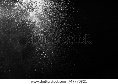 Freeze motion of white particles on black background. Powder explosion. Abstract dust overlay texture.  