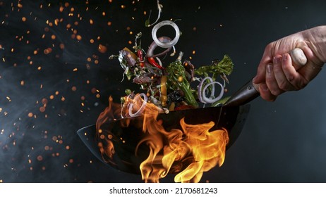 Freeze Motion of Wok Pan with Flying Ingredients in the Air and Fire Flames.