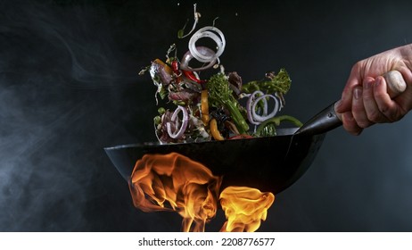 Freeze Motion of Wok Pan with Flying Ingredients in the Air and Fire Flames. - Powered by Shutterstock