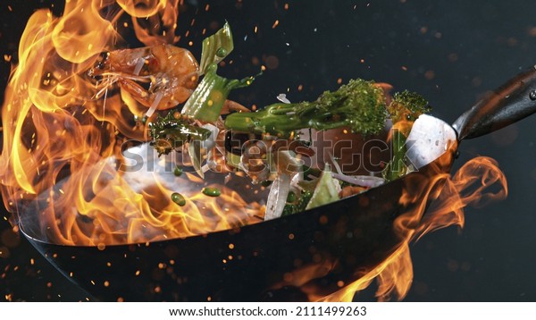 Freeze Motion of Wok Pan with Flying Ingredients\
in the Air and Fire\
Flames.