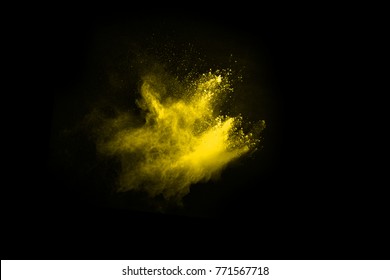 Freeze motion of yellow color powder exploding on black background.