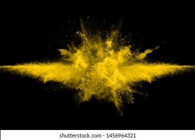 Freeze motion of yellow dust explosion isolated on black background.