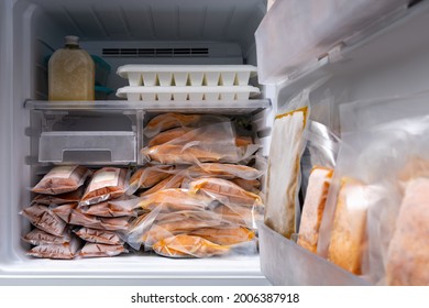 Freezer Of Modern Frigerator Full With Frozen Food Products In Quarantine Or Work From Home Period During Coronavirus Pandemic, Freeze Cooked Salmon In Vacuum Packs