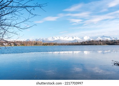 Freezing Icy Water On Westchester Lagoon With Reflection Of Chugach Mountains And Fall Landscape During October In Anchorage, Alaska. Peace Quiet View From Coastal Trail Ice Floes Floating