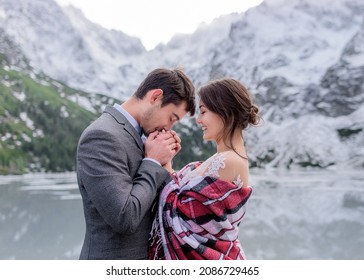 Freezing Wedding Couple Is Warming Up Together In The Winter Mountains In Front Of Frozen Lake