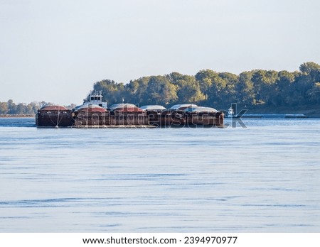 Freight barges approaching over the calm waters of the Mississippi river during low water conditions