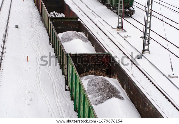 freight cars carry crushed stone.\
the arrival of the train to the station. railroad station. snow\
covered rails.  carriage in motion slight blur and bokeh\
effect.