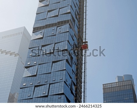 Freight construction elevator ascends to top of a skyscraper. Temporary elevator on a building under construction. Construction of skyscrapers. Red temporary elevator in a building under erection.