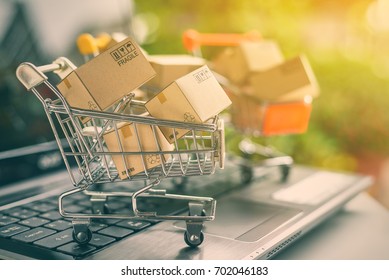 Freight or shipping service for online shopping or ecommerce concept : Paper boxes or cartons in metal shopping cart on a computer laptop keyboard. Customer always buy things via internet worldwide.